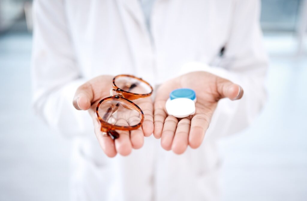 An eye doctor holding a pair of glasses in one hand and contact lens in the other hand
