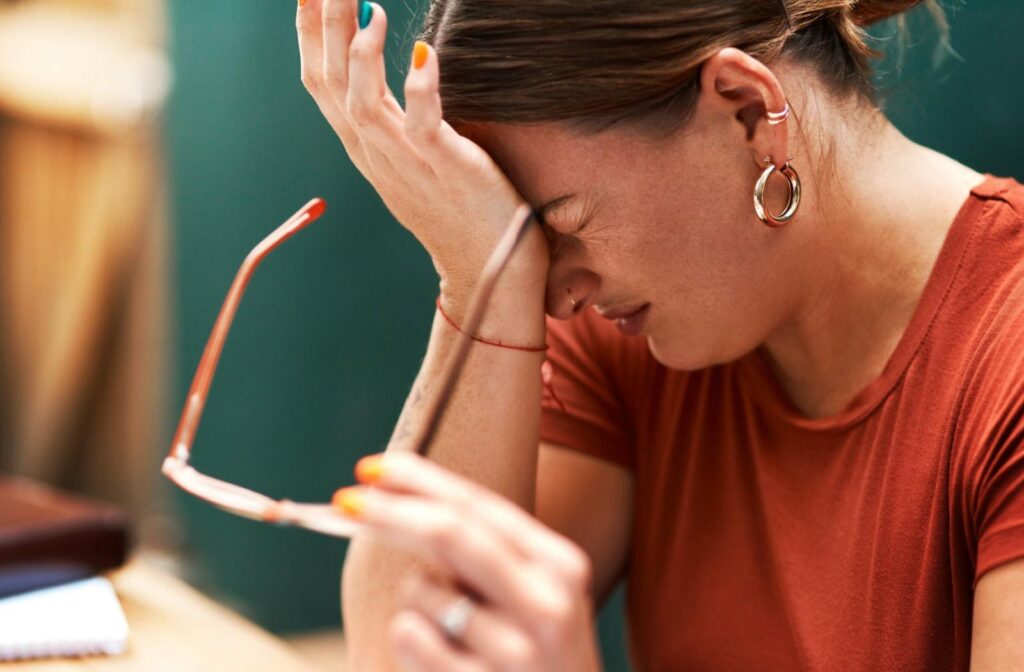 A person with their glasses removed rubbing their dry irritated eyes