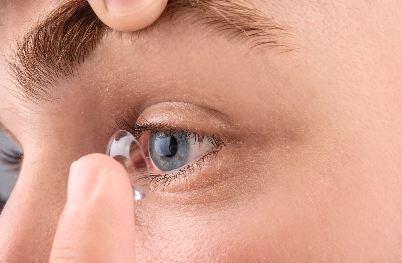 a close up of a person putting a contact lens in their eye